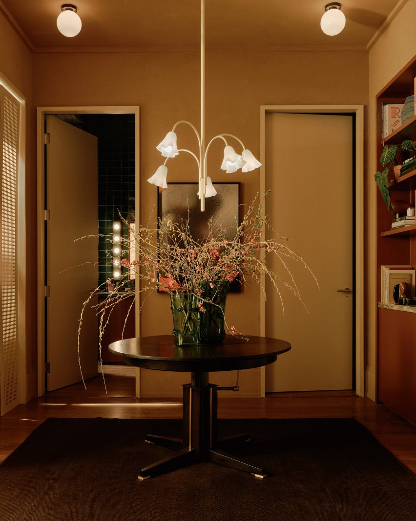 Foyer with a central table and a floral chandelier above