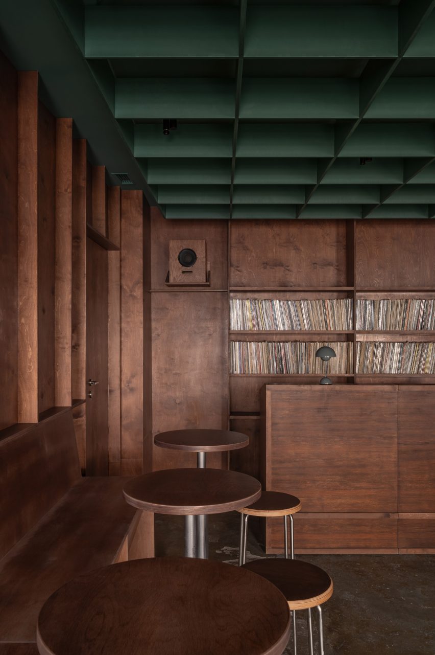 Bar with tables, a DJ booth and a vinyl record collection displayed behind by Mirzoyan Studio