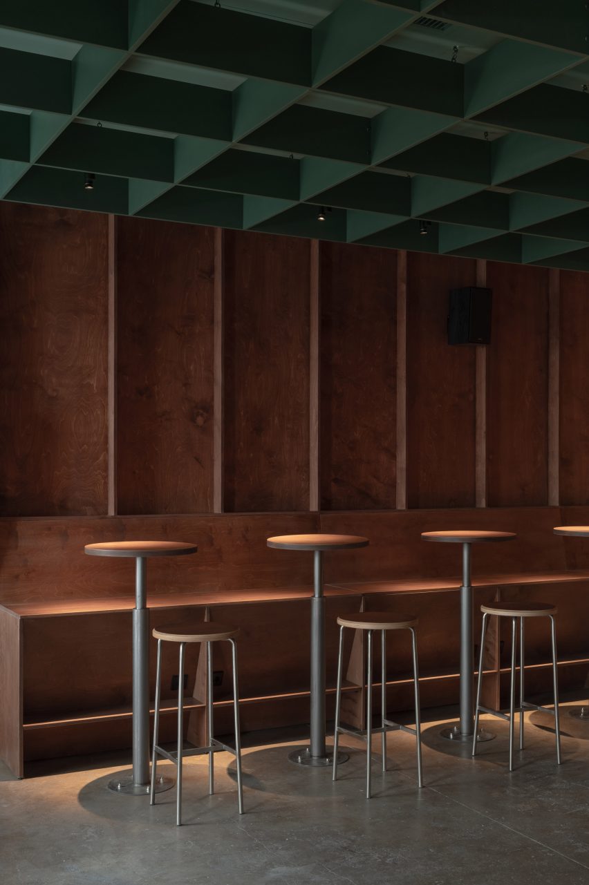 Row of tables and stools along a built-in plywood bench