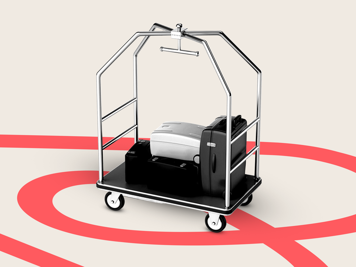 A luggage cart rolling over the Airbnb logo