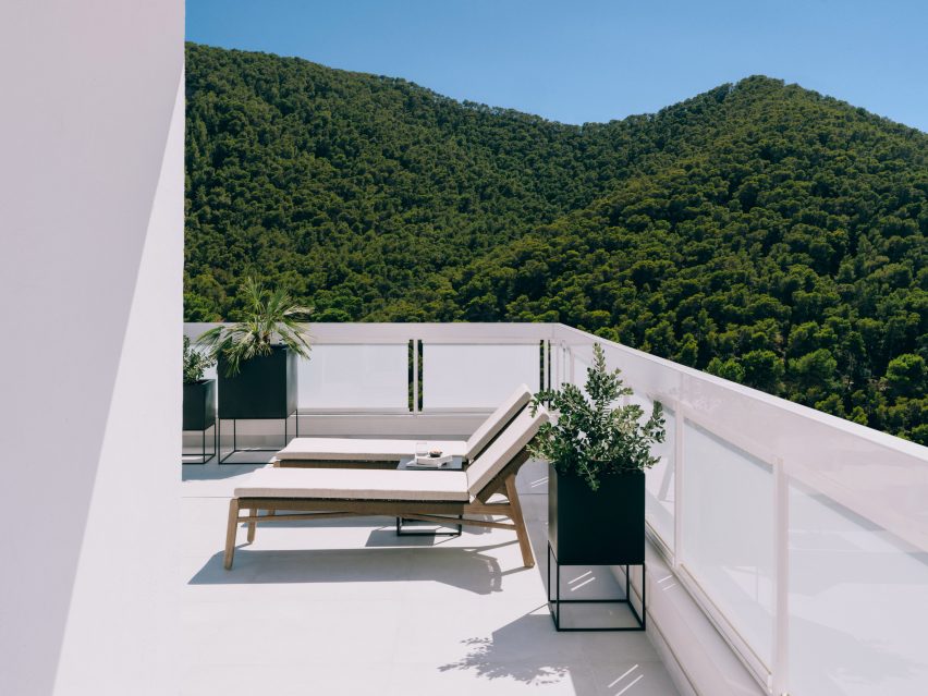 White balcony with loungers with verdant hills in the background