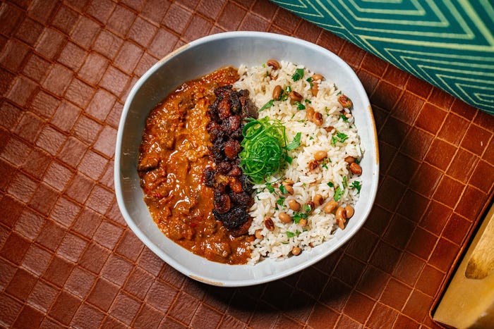 A bowl of buka, a red stew with rice, beans, and beef