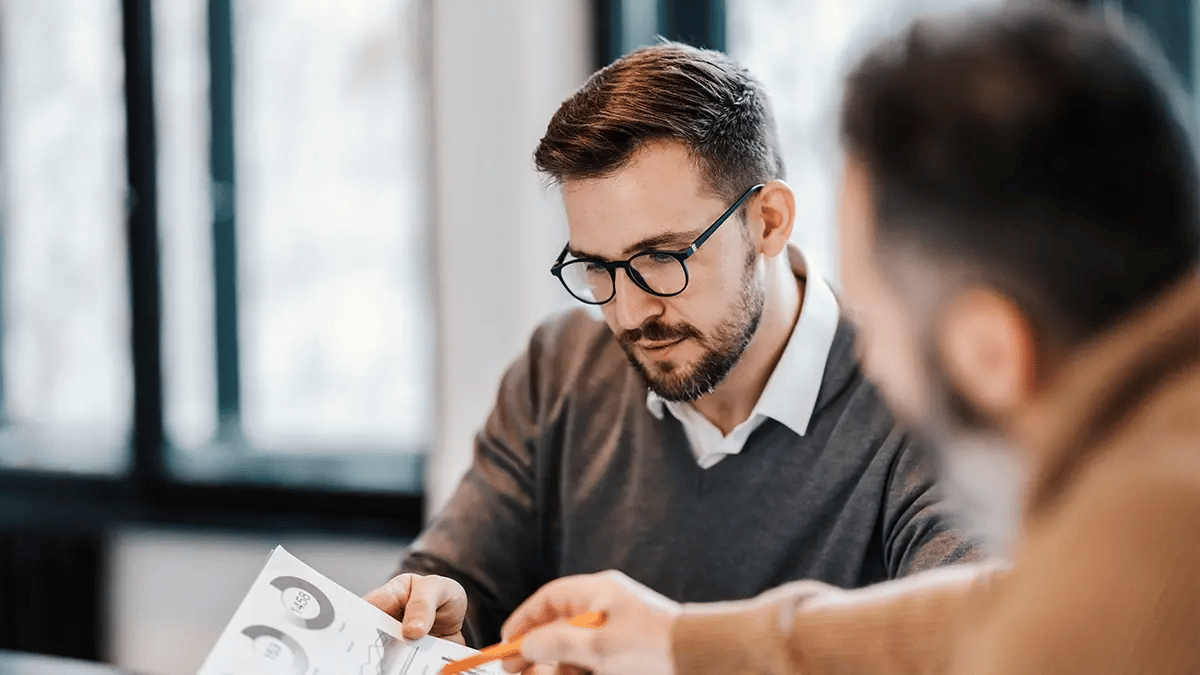 Two people looking down at a data sheet and discussing the stats.