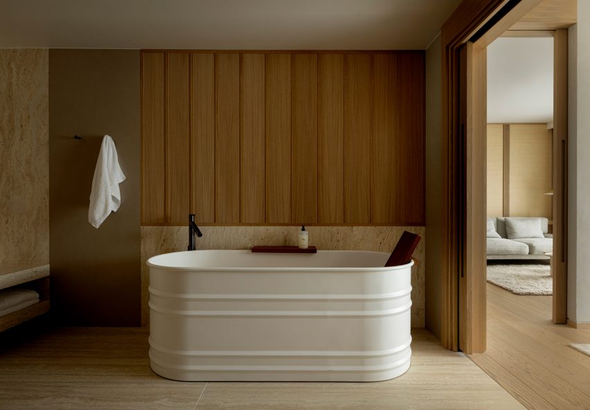 Deep white bathtub backed with wood-panelled wall