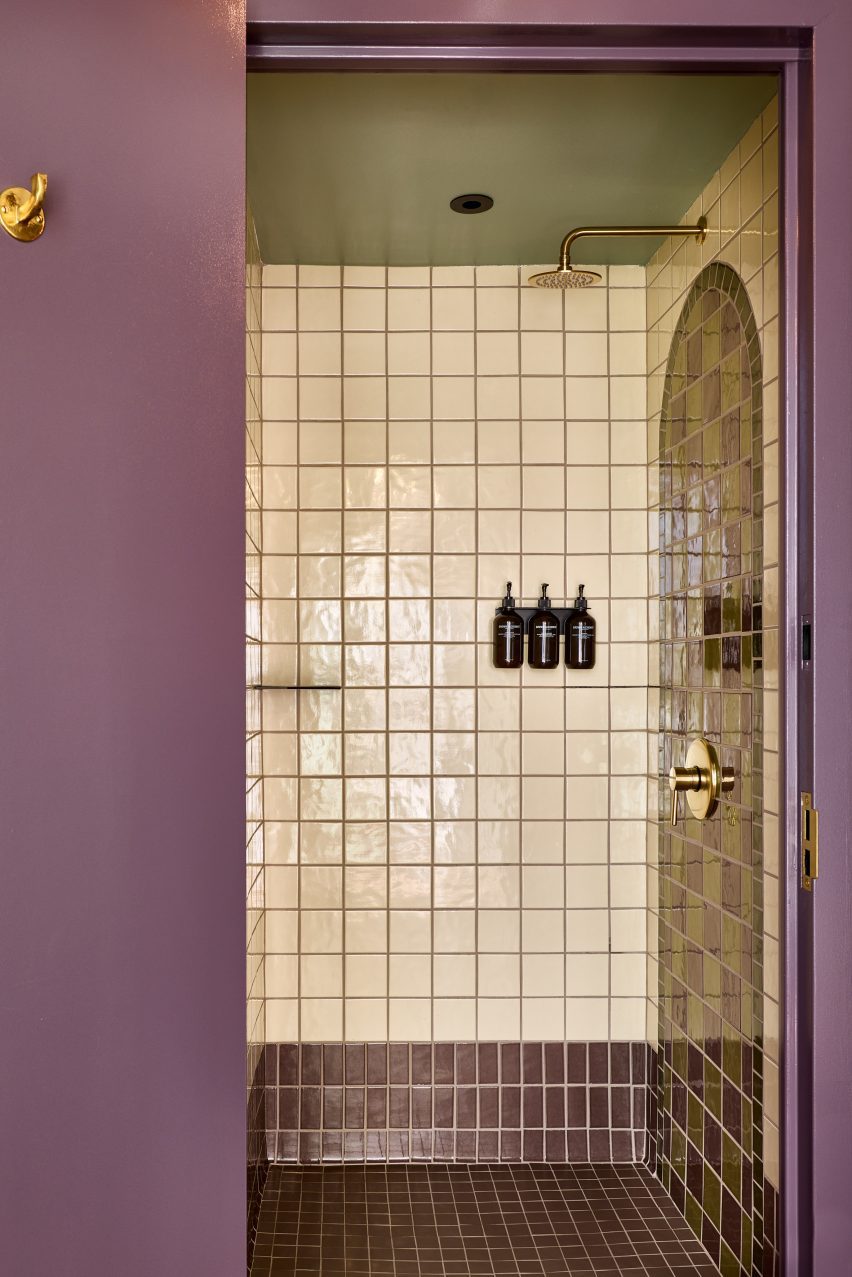 Shower with square beige tiles behind a purple door frame