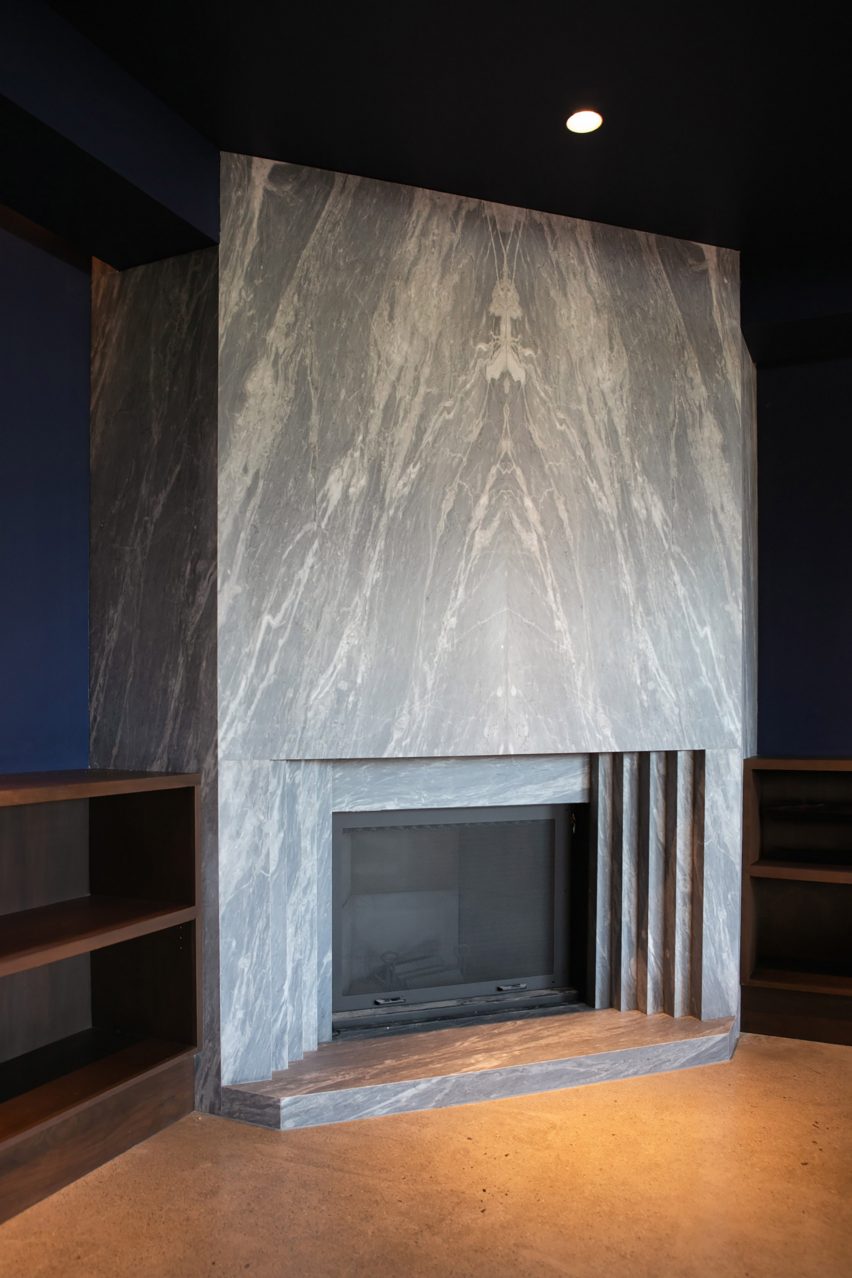 A large stone fireplace within a dark-toned reading nook