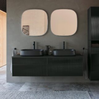 Double black vanity with two rounded sinks and matching taps, two rounded mirrors, and a tall black storage cabinet in a modern bathroom.