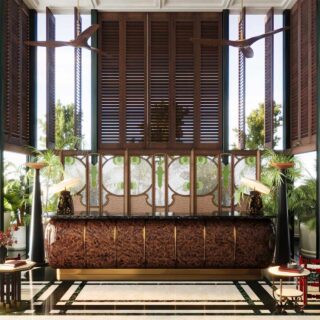 Luxurious hotel lobby with a curved dark marble reception desk, wooden slat walls, and lush tropical plants.