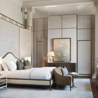 Luxurious hotel bedroom with a large bed, decorative folding screens, and ornate columns.
