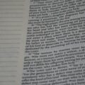 Close-up of a printed book page with dense, small serif text and a dotted left margin.