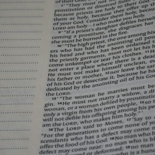 Close-up of a printed book page with dense, small serif text and a dotted left margin.