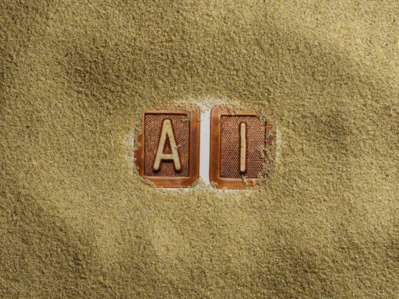 Two clay tiles with the letters A and I, partly buried in coarse sand.