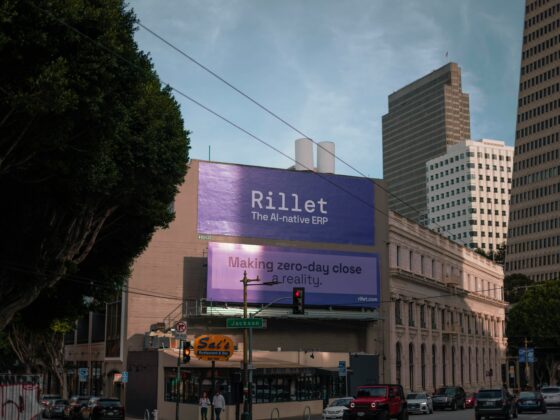 City street with a large purple billboard reading 'Rillet The AI-native ERP' above storefronts,Jackson Street sign, and tall office buildings to the right.