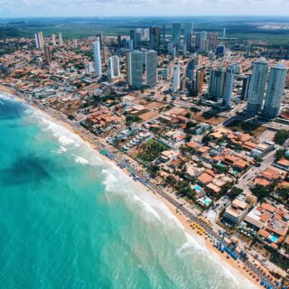 Aerial view of a coastal city with high-rise buildings along a sunny beach.