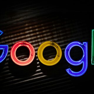 Colorful neon Google logo letters lit against a dark background.