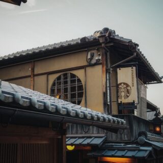 Traditional Japanese-style storefront with grey tiled roof, wooden beams, and a Starbucks banner hanging outside.