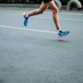A runner's legs in mid-stride on a track, wearing blue and orange athletic shoes with white socks.