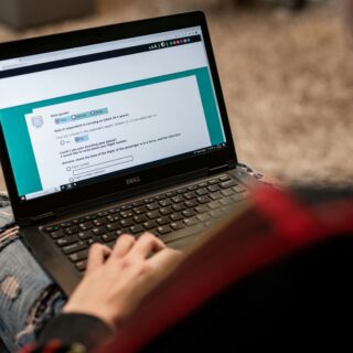Person using a Dell laptop outdoors, focused on a form displayed on the screen