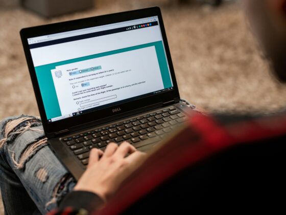 Person using a Dell laptop outdoors, focused on a form displayed on the screen