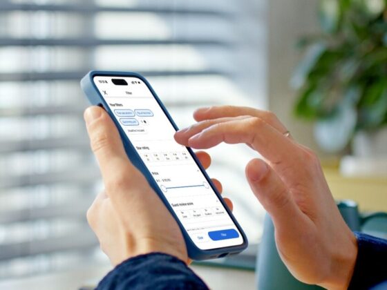 Person holding a smartphone showing a travel app on screen, with Agoda logo in the blurred background.