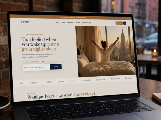 Laptop screen shows a hotel booking site (Sonder) with a person stretching in bed beside a city view; a coffee cup sits on the table nearby.