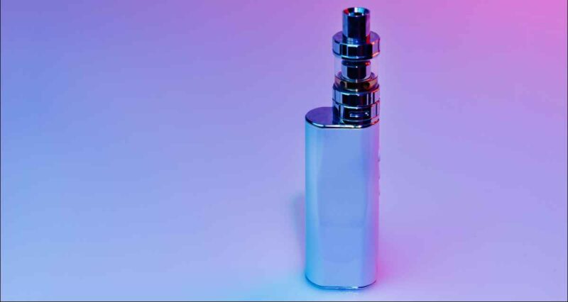 Silvery vape mod standing upright on a blue-pink gradient background.
