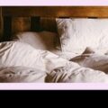 Banner ad on a pink background with bold slogans left ('Room revenue is your baseline') and right ('Not your business model'), a centered photo of an unmade bed, and a black bottom bar showing the MEWS logo and a 'Get the metrics that matter guide' callout.