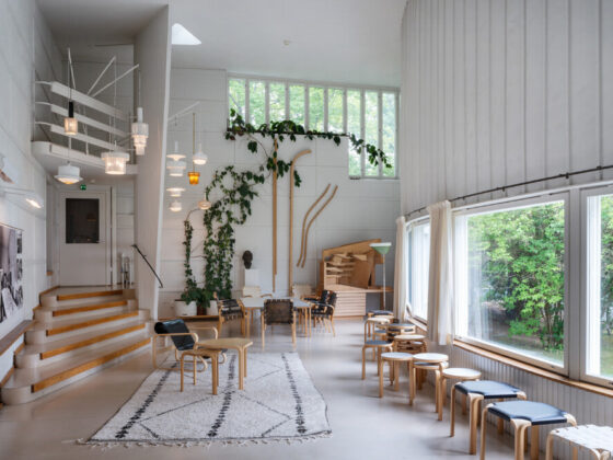 Bright, airy interior with white walls, wooden seating, and large windows framed by greenery a calm gathering space.