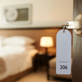 Hotel room door with key tag reading 206, blurred bedroom and lamp in the background.