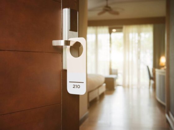 Hotel room door with a white keycard hanging from the handle, room 210 visible in a softly lit hallway.