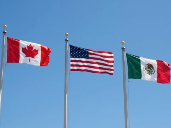Three national flags—Canada, United States, and Mexico—flying on flagpoles against a clear blue sky.