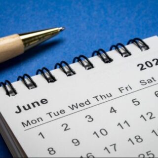 Close-up of a June 2026 calendar page with a pencil on a blue surface.