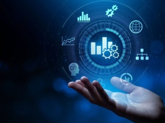 Hands under a glowing circular holographic interface with charts, gears, and globe—symbolizing data analytics and digital tech.