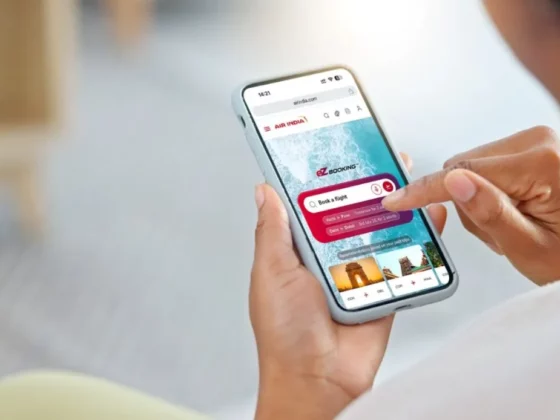 Person holds a smartphone displaying a flight-booking app with a 'Book a Flight' search bar.