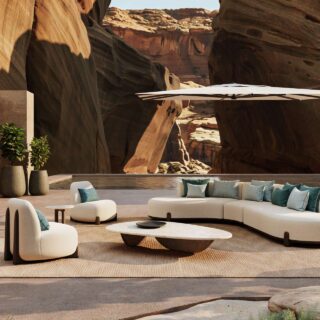 Luxurious outdoor lounge built into a desert canyon, with curved white seating, teal pillows, a low coffee table, and a large white canopy umbrella.