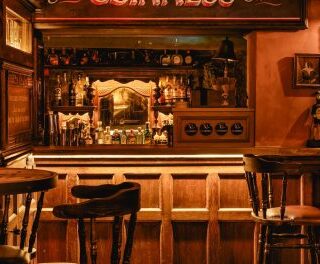 Cozy wooden bar interior with stools, warm amber lighting, and framed photos on the walls.