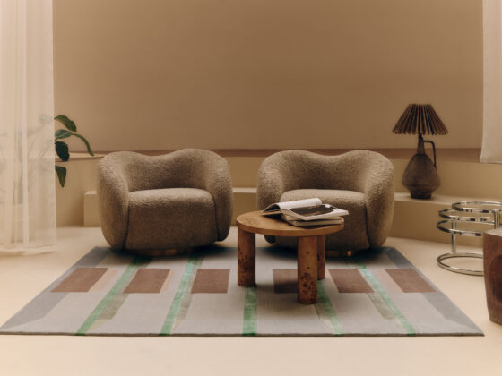 Two plush beige armchairs face each other with a small round wooden table between them in a neutral living room.