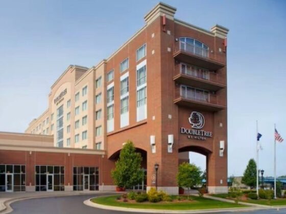 Brick DoubleTree by Hilton hotel exterior with arched entrance and flagpoles by the driveway.