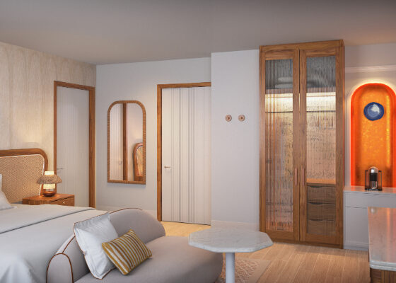 Hotel room with a king bed, beige sofa, wall mirror, wooden wardrobe, marble coffee table, and an orange backlit tea station.