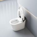 White modern toilet with open lid in a bright, minimalist bathroom featuring a wall with angled lighting strip nearby.