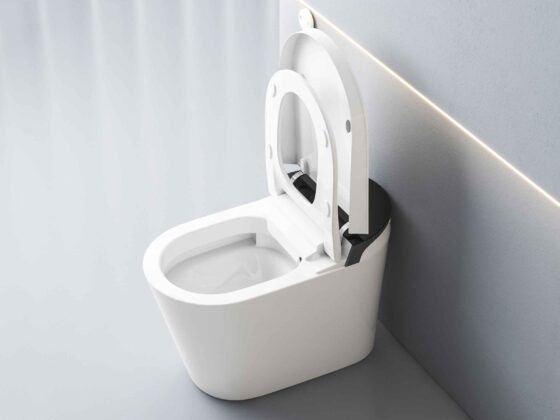 White modern toilet with open lid in a bright, minimalist bathroom featuring a wall with angled lighting strip nearby.