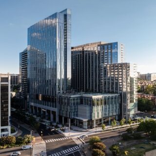 Modern glass skyscrapers in a downtown business district, seen from an elevated street-level view.