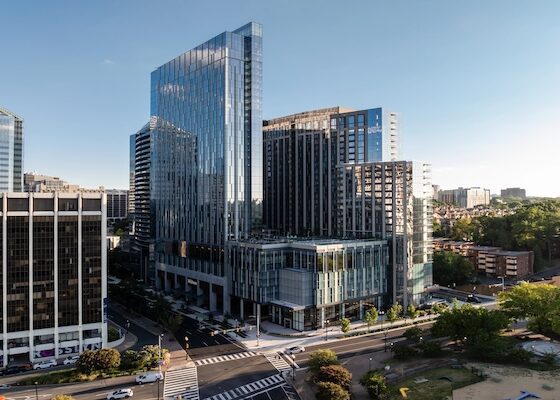 Modern glass skyscrapers in a downtown business district, seen from an elevated street-level view.