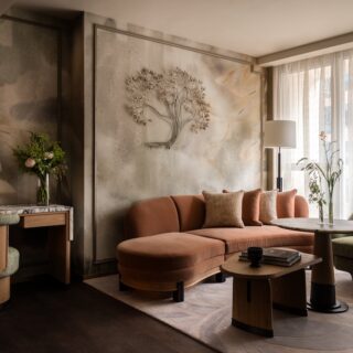 Luxe living room with a curved peach sofa, green armchair, round coffee table, and sheer curtain backdrop.