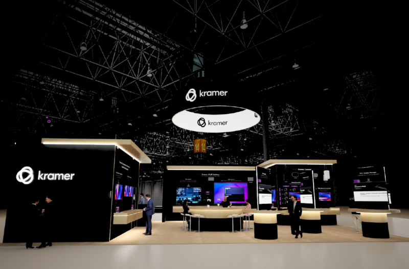 Trade show booth with Kramer branding, large black walls, circular suspended sign, and multiple product displays with people talking around a curved counter.