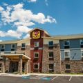 Exterior view of a My Place hotel with stone columns, blue siding, and a covered entry on a sunny day