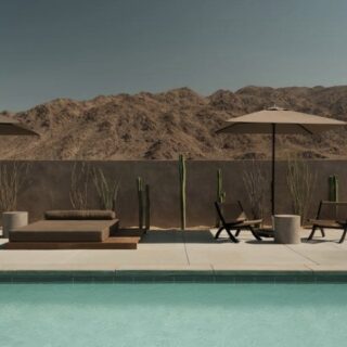 Pool deck with sun loungers, umbrellas, and cactus against a desert mountain backdrop.
