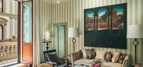 Living room with green striped walls, a beige sofa with colorful cushions, and large arched artwork above a coffee table.