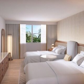 Hotel room with two neatly made white beds, a bedside table, and a large window showing palm trees outside.