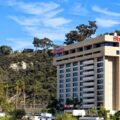 Sheraton hotel building on a hillside under a blue sky with palm trees in foreground